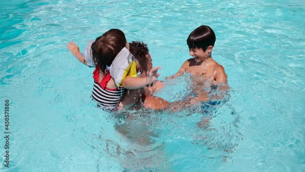 Father playing with children splashing water in swimming pool Father playing with children splashing water in swimming pool