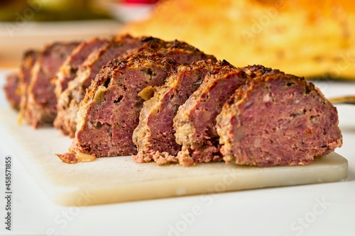 Sliced meatlof on kitchen board, blurred bread on background.