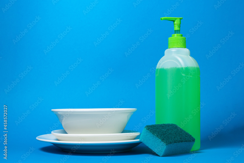 Detergent next to clean plates on a blue background. Ecological household chemicals