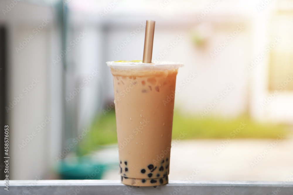 Ice milk tea and bubble boba in plastic cup put on bar steel and sun light Ice milk tea and bubble boba in plastic cup put on bar steel and sun light