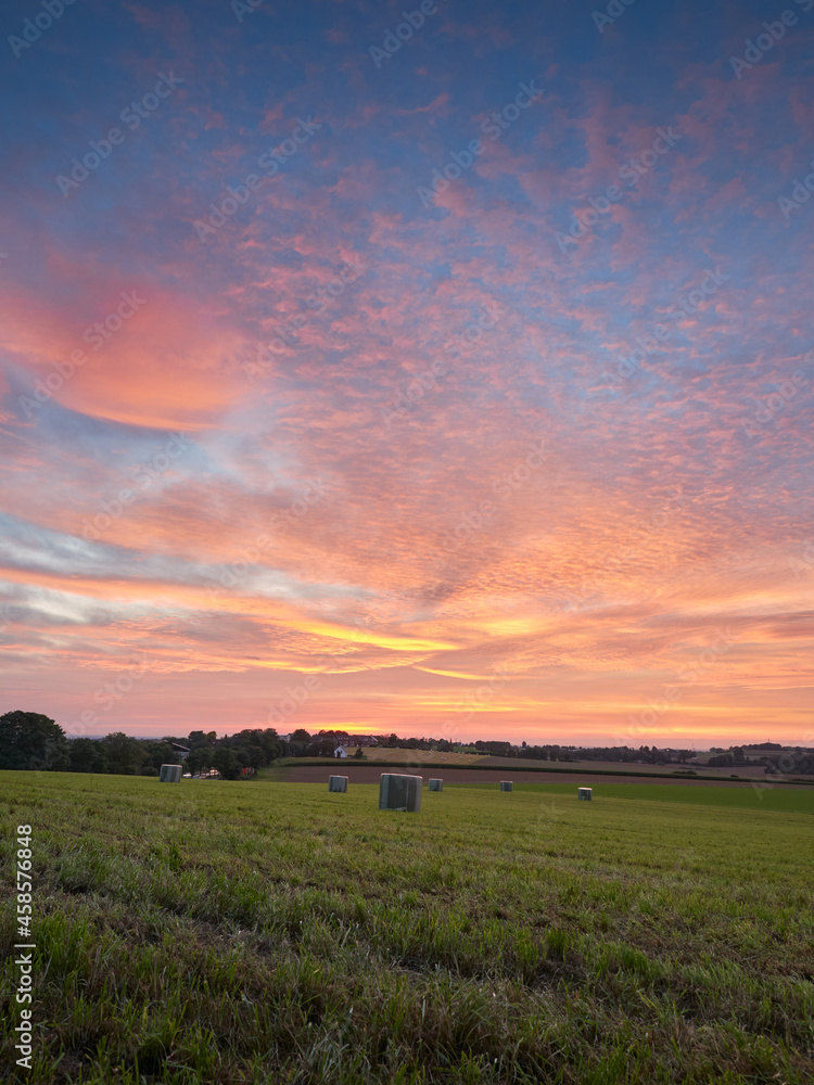 Ratingen, Germany - Beautiful sunset in the Bergisches Land region. Meadow in straw bales. Rural landscape.