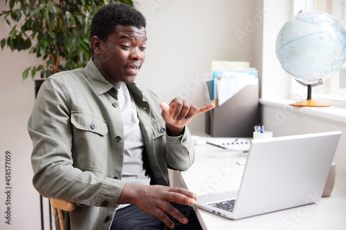 Young Man Having Conversation Using Sign Language On Laptop At Home