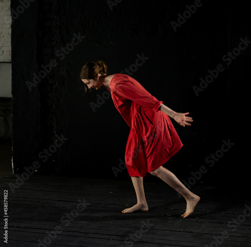 woman in a red dress on a black background dances, waving her hands. blur, smear