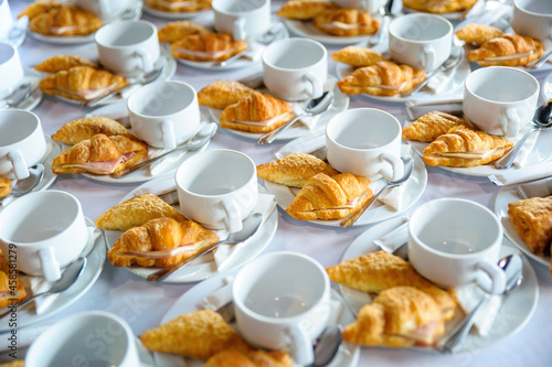 many dishes of croissant sandwich with coffee cup set up on white table for tea break time at business meeting conference refreshing up in afternoon