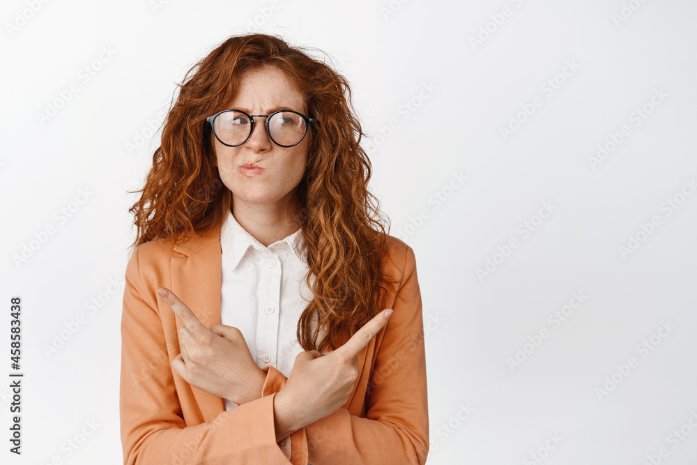 Young saleswoman facing complicating decision, frowning puzzled and pointing sideways, cant choose, standing thoughtful against white background