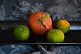 tangerines are lying on a black tray on a carelessly thrown tablecloth