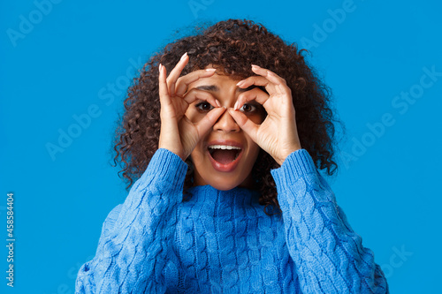 Surprised and fascinated, excited african-american woman looking through circles okay gesture like holding binocular and checking out impressed awesome promo, smiling amused