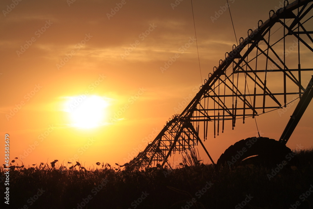Φωτογραφία Irrigation System silhouette at Sunset with a colorful sky and clouds with the Sun south of Sterling Kansas USA out in the country