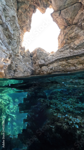 Underwater split photo of beautiful paradise pebble rocky bay of Kaladi with turquoise crystal clear sea and small caves  Kithira island  Ionian  Greece