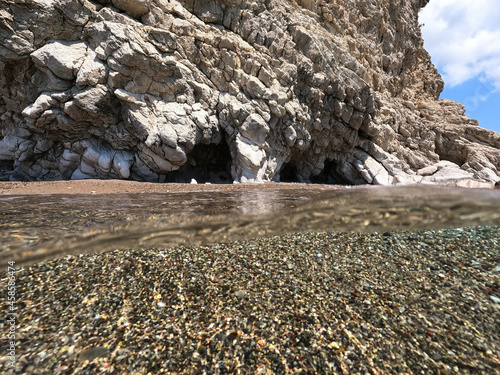 Underwater split photo of beautiful paradise pebble rocky bay of Kaladi with turquoise crystal clear sea and small caves, Kithira island, Ionian, Greece photo