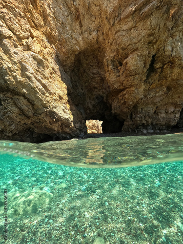 Underwater split photo of beautiful paradise pebble rocky bay of Kaladi with turquoise crystal clear sea and small caves, Kithira island, Ionian, Greece © aerial-drone