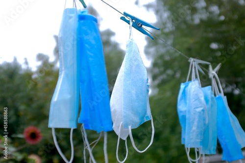 Disposable blue medical masks hang from a clothesline. Absurdity - washing disposable items. Pandemic concept.