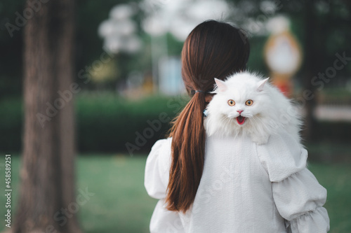 Asian woman holding a white cat in a park