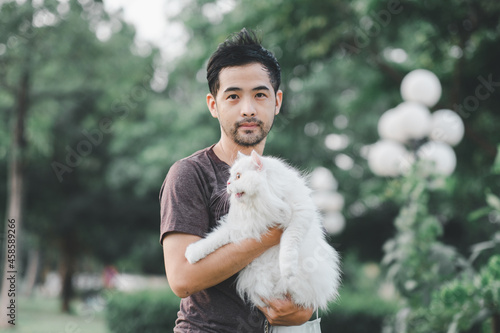 Man holding a white cat in a park