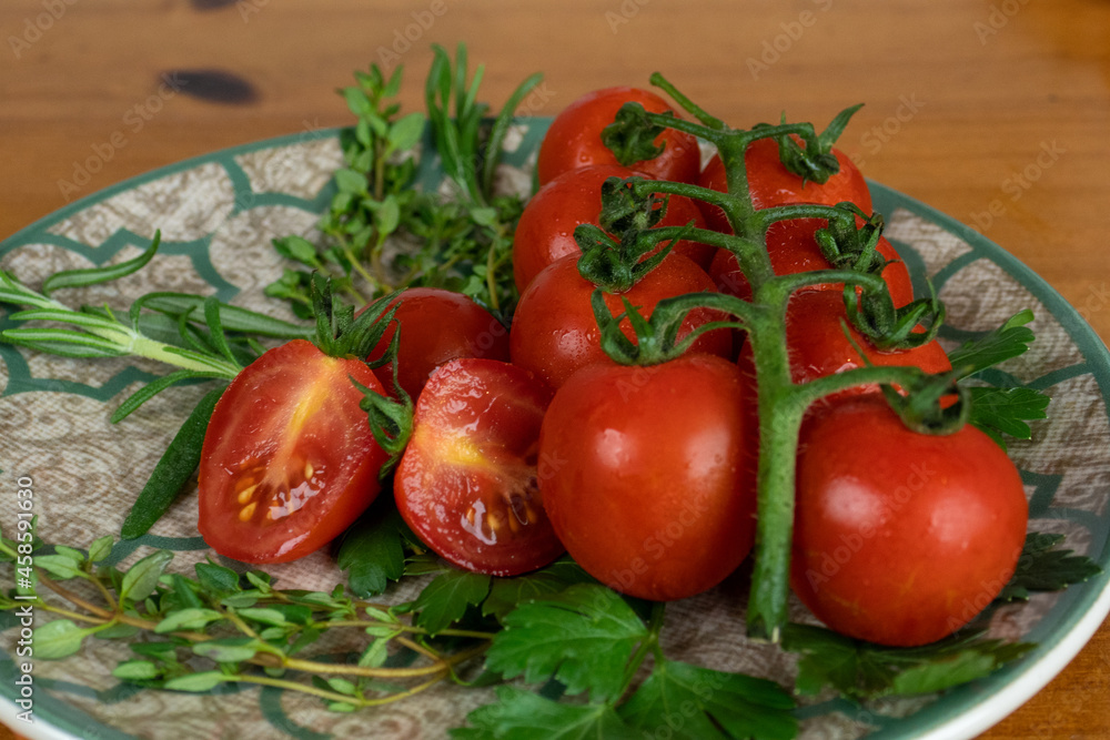 cherry tomatoes on wooden table over white plate with olive oil with herbs. light background, close-up photo cherry tomatoes on wooden table over white plate with olive oil with herbs. light background, close-up photo
