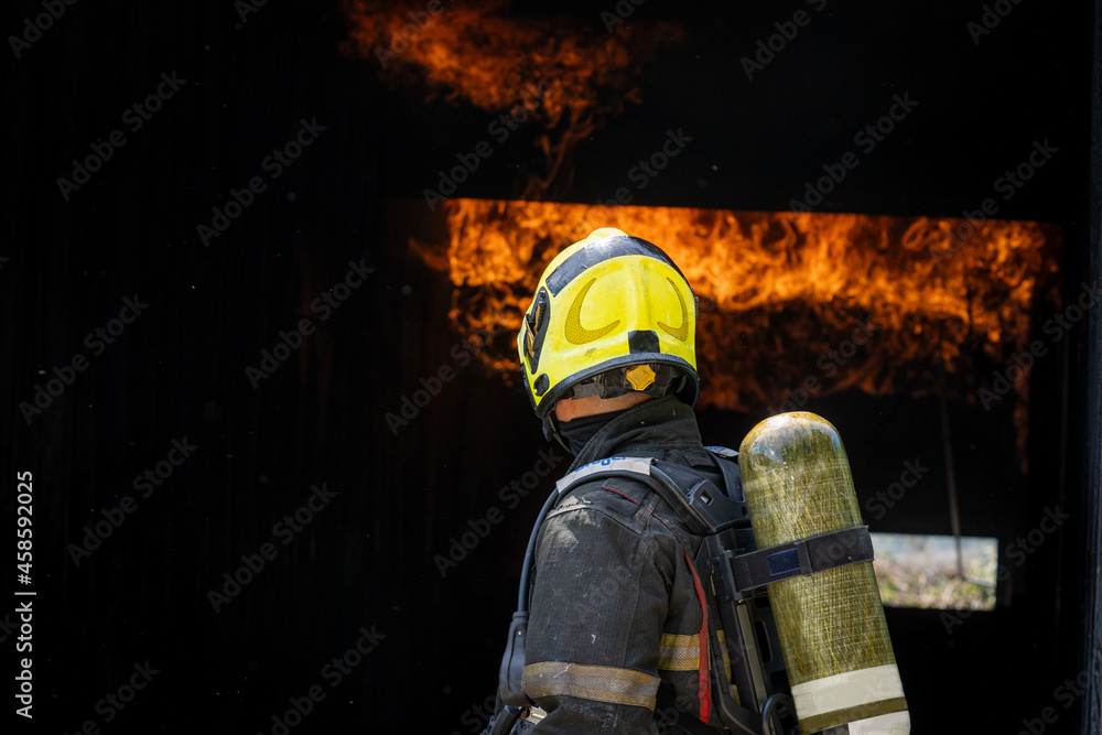 Fototapeta premium Fireman wearing suit for safety using water and extinguisher to fighting with fire flame in an emergency situation.