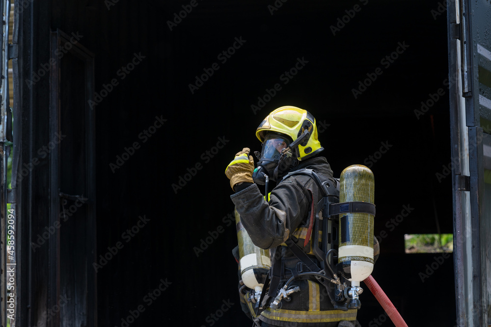Fototapeta premium Fireman extinguishes a fire,Firefighter water spray by high pressure fire hose in an emergency situation.
