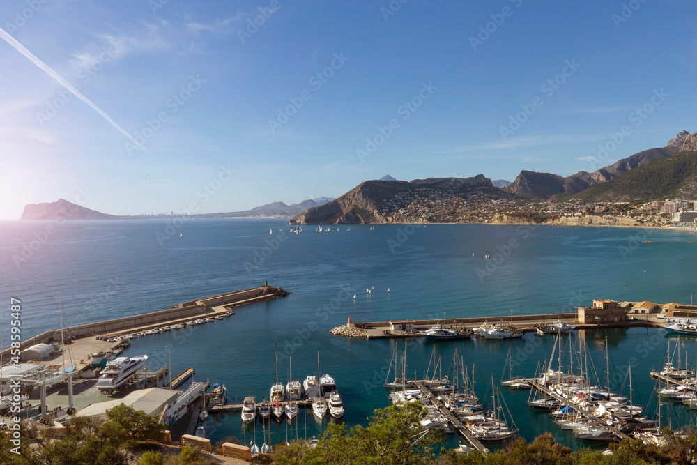 Obraz premium Coastline of the Mediterranean resort of Calpe, Spain with sea and yachts, lake, skyscrapers and mountain range.