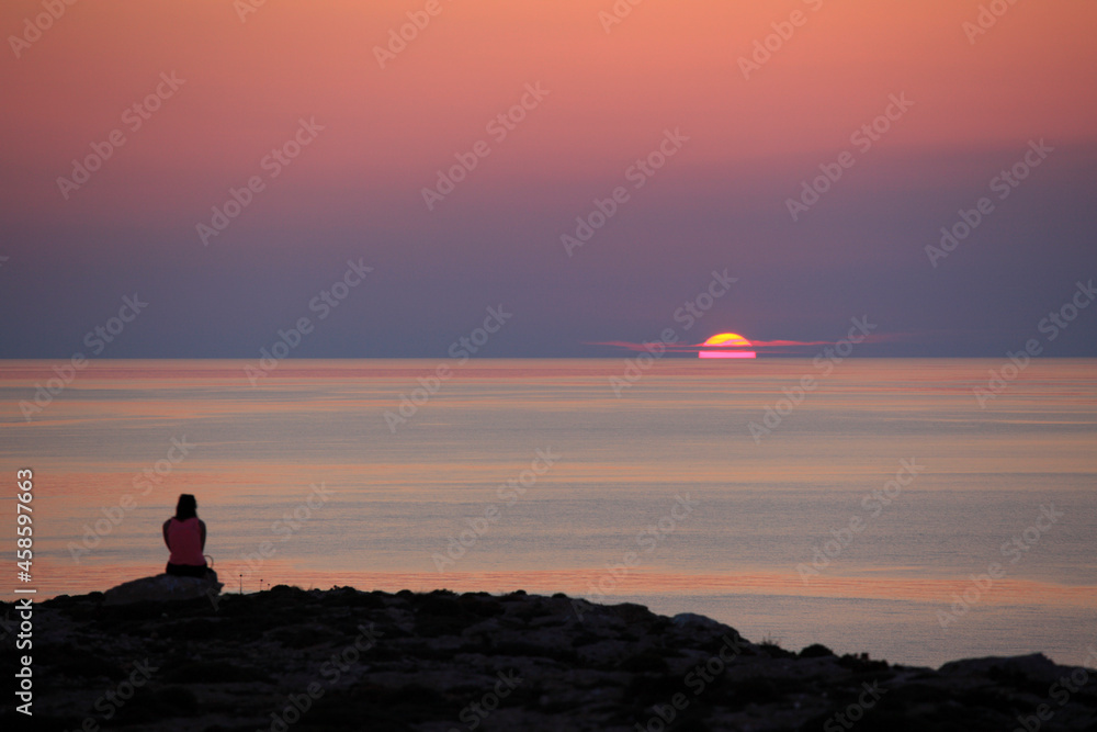 Woman watching the sunset in Lampedusa, Sicily, Italy
