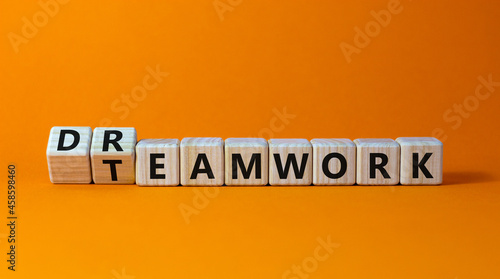 Teamwork and dream work symbol. Turned wooden cubes and changed the word 'dreamwork' to 'teamwork'. Beautiful orange background. Business, teamwork and dream work concept, copy space. photo