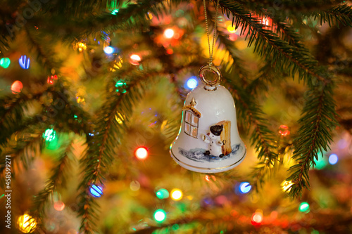 Ornate white porcelain bell - handmade Christmas ornament hanging on a spruce branch