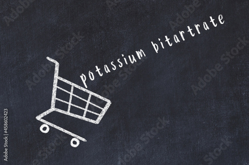 Chalk drawing of shopping cart and word potassium bitartrate on black chalboard. Concept of globalization and mass consuming photo