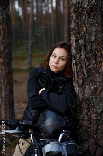 a woman on a motorcycle in nature. motorcyclist walk through the forest