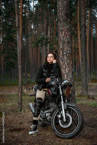 a woman on a motorcycle in nature. motorcyclist walk through the forest © alas_spb