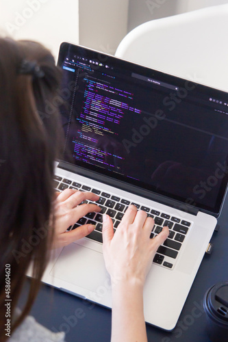 A programmer coding on a laptop in the workplace