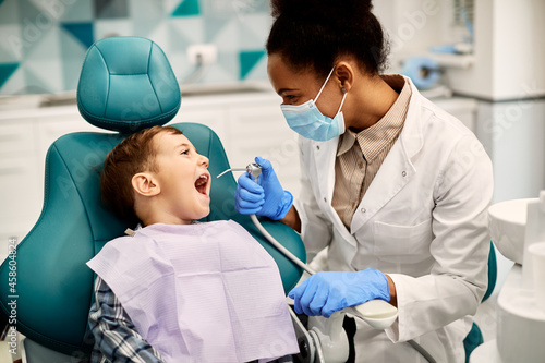 African American dentist's examining teeth of a small boy at dental clinic. photo
