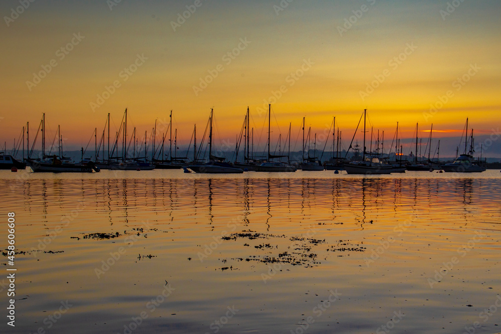 Harbour sunrise with fishng boats and orange sky water reflections