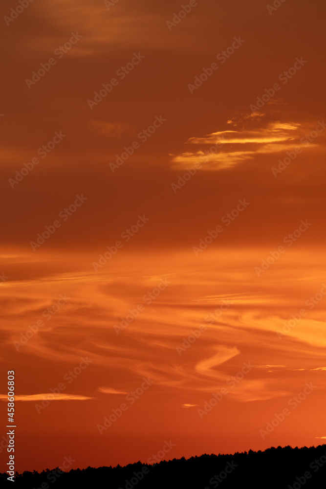 Orange sunset with flowing clouds and mountain range