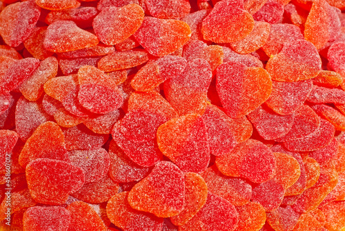 Texture of red and orange candies. Sweets on a pile close up. Sweets shop window.