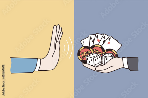 Refusal from gambling lifestyle concept. Human hand making no refusal denying sign from another hand holding cards and playing chips 
