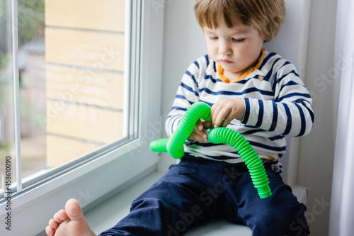 Colorful anti-stress fidget push pop tube toys for children. Flexible corrugated pipe in kids hands. Boy playing with sensory toys. Fun playing for developing imagination and fine motor skills. photo