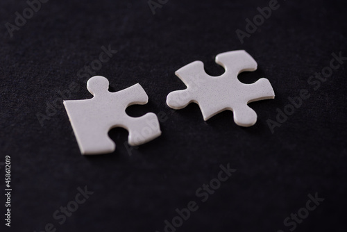 Two white jigsaw puzzles isolated on black background
