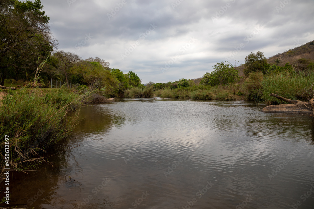 A river in the African bush with clouds in the sky. 
