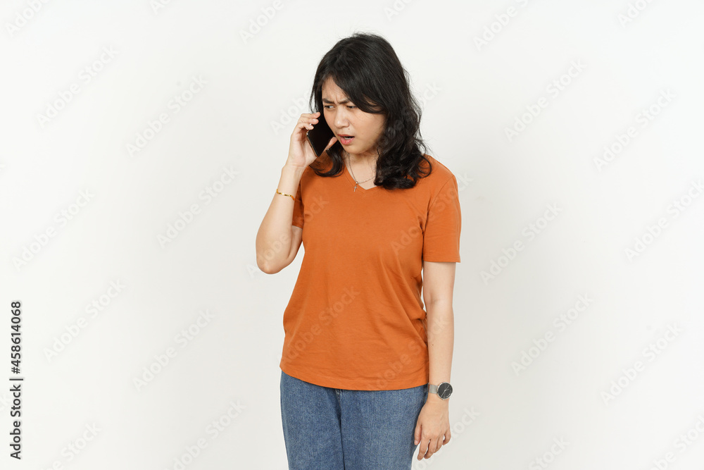 Talking on the phone with serious angry face expression of beautiful asian woman Wearing orange T-shirt isolated on white background Talking on the phone with serious angry face expression of beautiful asian woman Wearing orange T-shirt isolated on white background