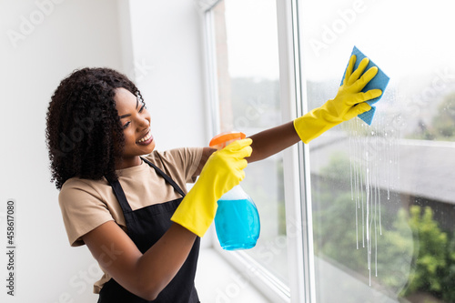 African happy young woman housewife washes a window