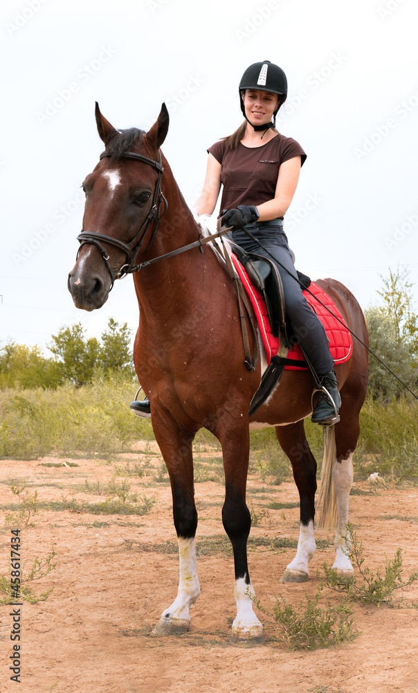 Happy girl sits astride a piebald horse in the field. Happy girl sits astride a piebald horse in the field.