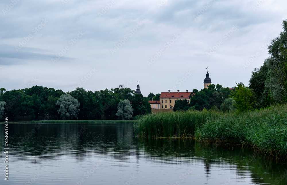 Lake overlooking the ancient castle of the Radziwills Nesvizh, Belarus. Beautiful summer landscape with architectural elements.