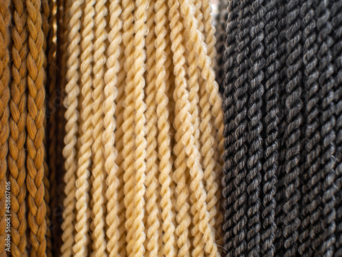 Dark brown, light brown and black artificial braided hair background. Selective focus.