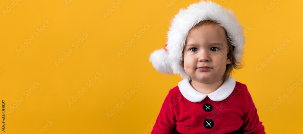 Banner Portraite Cute Happy Cheerful Chubby Baby Girl in Santa Suit Looking On Camera At Yellow Background. Child Play Christmas Scene Celebrating Birthday. Kid Have Fun Spend New Year Time Copy Space Banner Portraite Cute Happy Cheerful Chubby Baby Girl in Santa Suit Looking On Camera At Yellow Background. Child Play Christmas Scene Celebrating Birthday. Kid Have Fun Spend New Year Time Copy Space