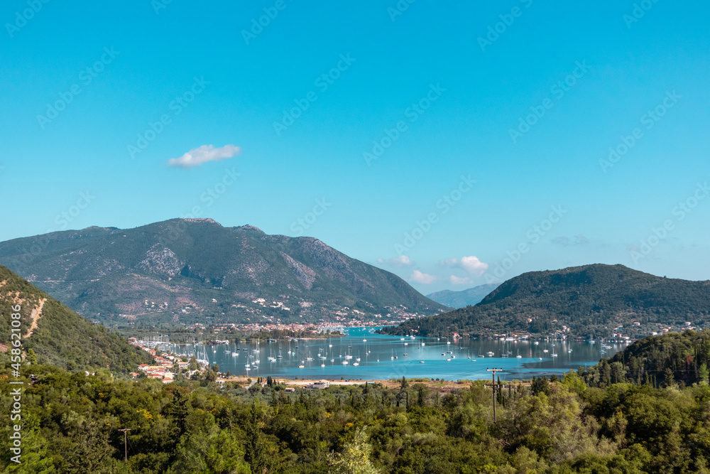 Bright Vlicho bay view from hills of Lefkada island Katochori village, Ionian Islands, Greece. Boats, blue sea and sky surrounded by summer greenery