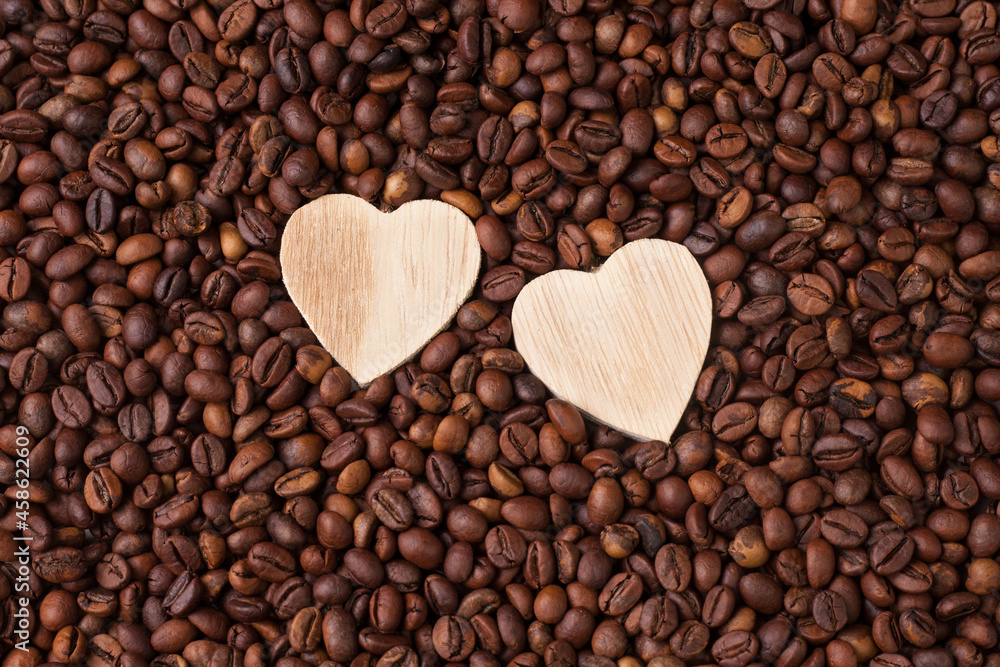 Macro photography of roasted brown coffee beans. A flat composition. Close-up, top view. Two wooden hearts. Love for coffee. Macro photography of roasted brown coffee beans. A flat composition. Close-up, top view. Two wooden hearts. Love for coffee.
