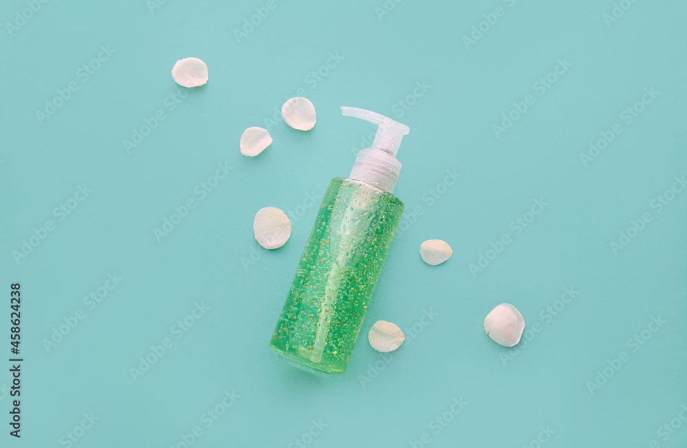 Bottle of cosmetic product and flower petals on color background Bottle of cosmetic product and flower petals on color background