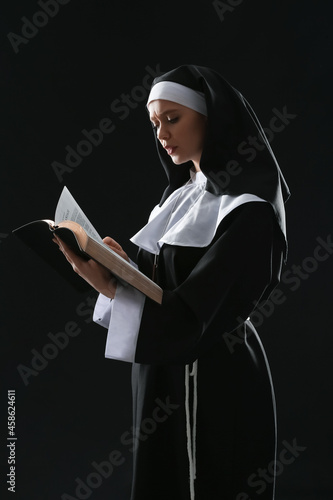 Young nun with Bible on dar...