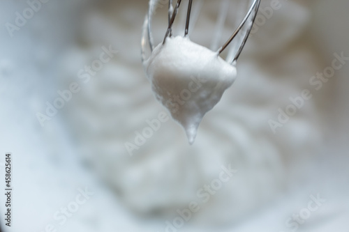 Whipped egg whites - beaten italian meringue on a whisk, closeup, copy space. Process of cooking meringue. Baking dessert concept. High quality photo photo