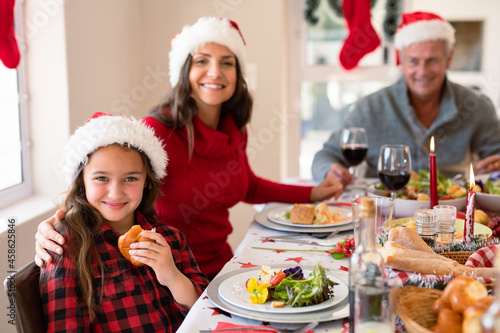 Happy caucasian mother and daughter wearing santa hats looking at camera at christmas time © wavebreak3