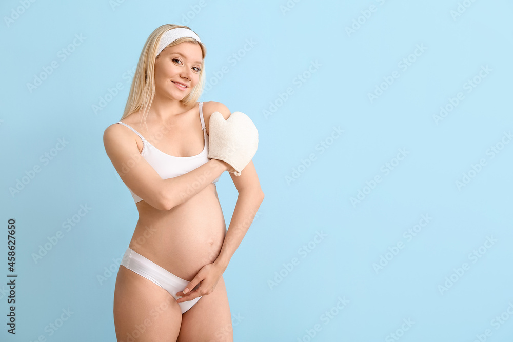 Beautiful pregnant young woman with massage mitten on color background Beautiful pregnant young woman with massage mitten on color background